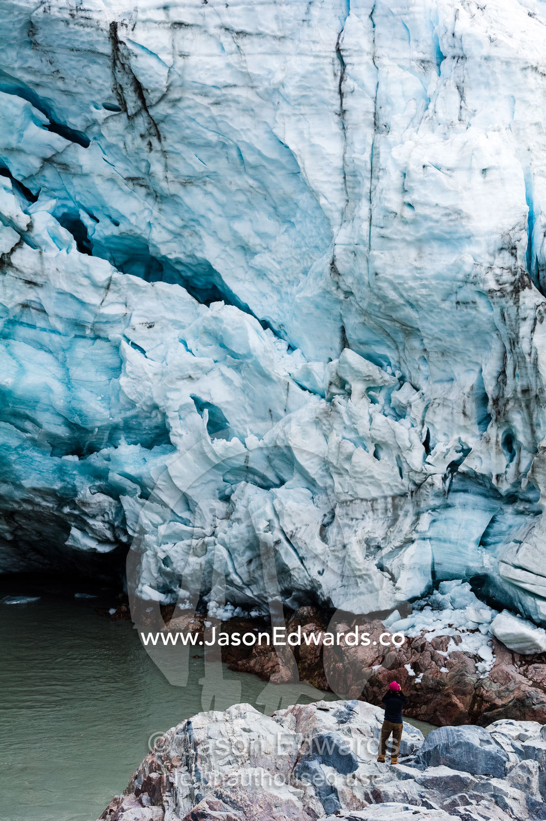 A hiker photographs a glacier fracture zone from a dangerous position beneath the ice. Qinnguata Kuussua River, Russell Glacier, Greenland Ice Sheet, Qeqqata Municipality, Kangerlussuaq, Greenland.