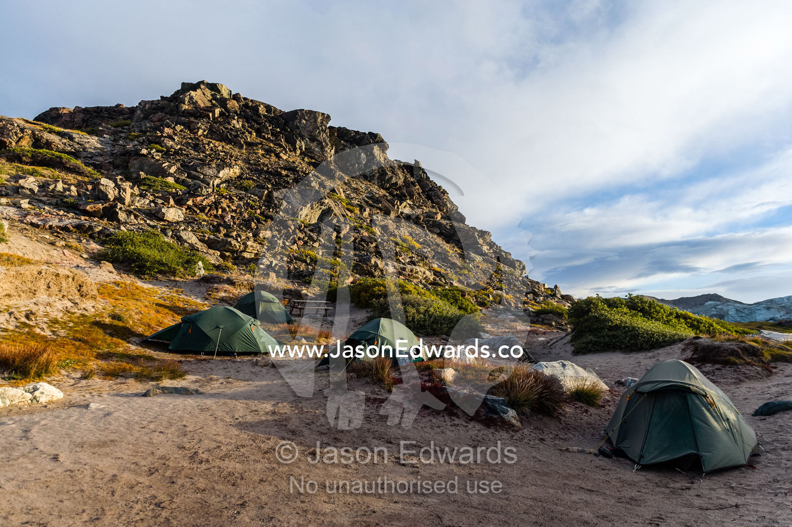 A tented campsite in the shadow of a hill on the arctic tundra. Russell Glacier, Greenland Ice Sheet, Qeqqata Municipality, Kangerlussuaq, Greenland.