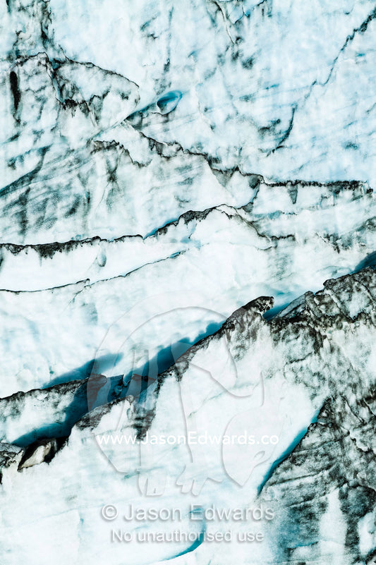 Erosion from ice against rock deposits silt and soil sediment on the edges of ice blades along the fracture zone of a glacier. Russell Glacier, Greenland Ice Sheet, Qeqqata Municipality, Kangerlussuaq, Greenland.