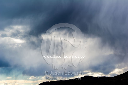 A rainstorm descends over the mountaintops of a fjord. Kangerlussuaq Fjord, Kangerlussuaq, Qeqqata Municipality, Greenland.