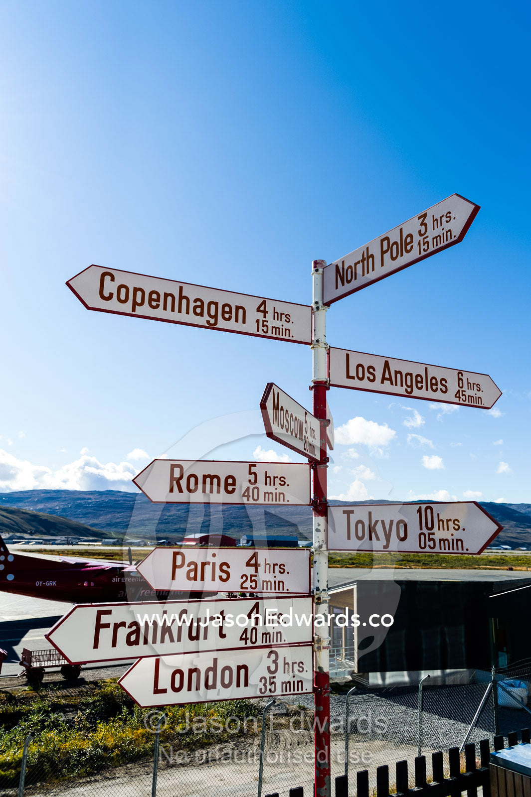 Directional signs pointing to cities around the world and their distance from Greenland. Kangerlussuaq, Qeqqata Municipality, Greenland.