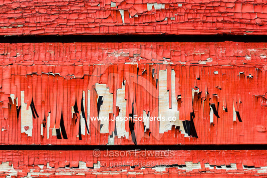 Red paint peeling from a weathered timber cottage wall. Kangerlussuaq, Qeqqata Municipality, Greenland.
