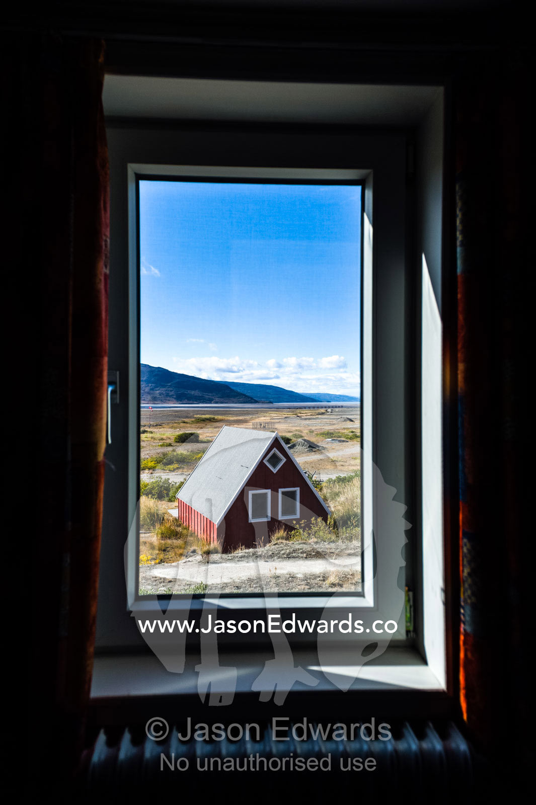 A cottage on the tundra viewed through a weather-sealed window. Kangerlussuaq, Qeqqata Municipality, Greenland.