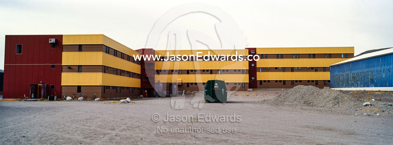 A linear apartment complex and barren carpark in an arctic village. Kangerlussuaq, Qeqqata Municipality, Greenland.