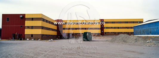A linear apartment complex and barren carpark in an arctic village. Kangerlussuaq, Qeqqata Municipality, Greenland.