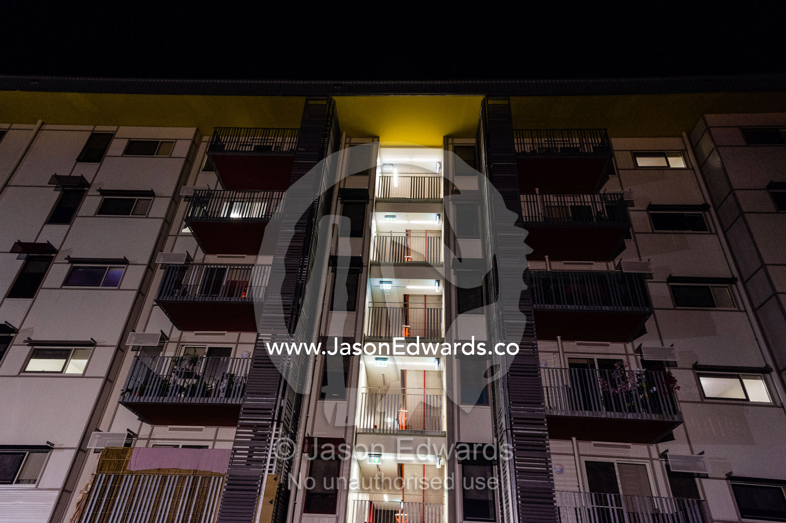 An inner city apartment block facade with windows and balconies at night. Richmond, Melbourne, Victoria, Australia.