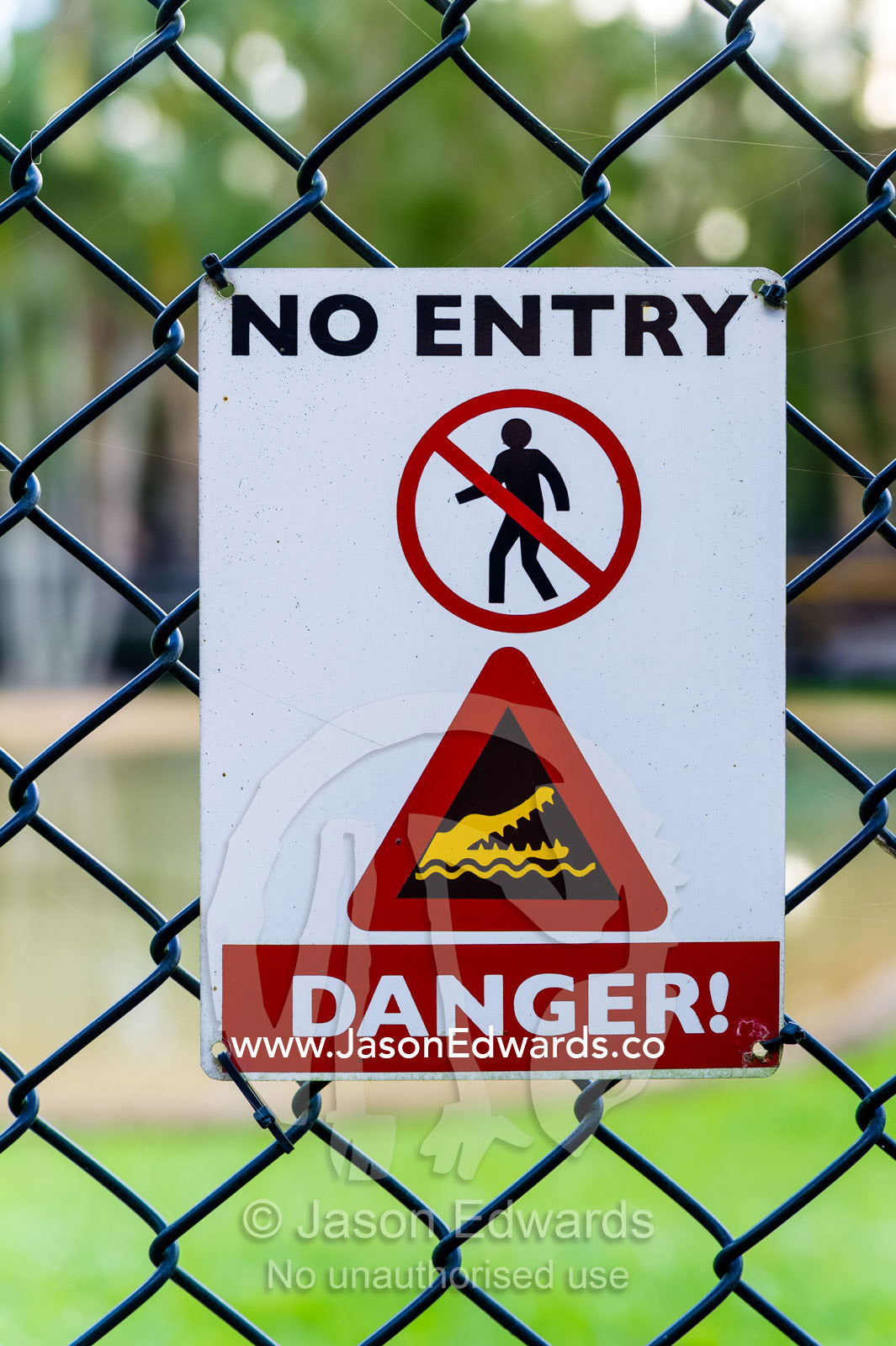 A sign warns of a deadly Saltwater Crocodile behind a safety fence in a zoo. Australia Zoo, Beerwah, Sunshine Coast, Queensland, Australia.