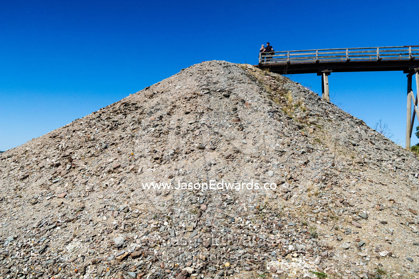 A tall mullock heap of sandstone and slate next to a gold mine Poppet Head. Sovereign Hill, Ballarat, Victoria, Australia.