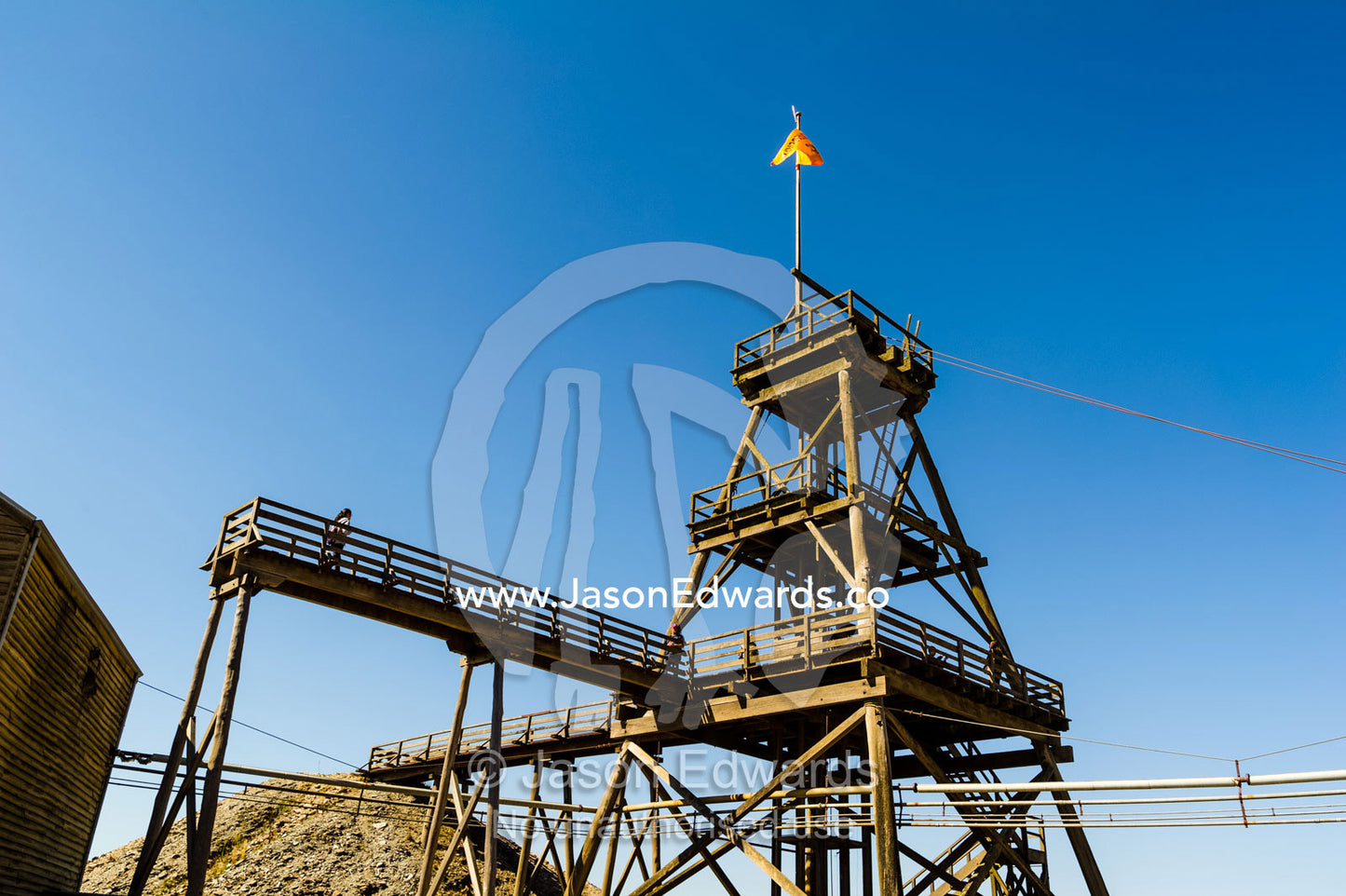 A timber Poppet Head towers above mullock heap and gold mine shaft in a gold mine town museum. Sovereign Hill, Ballarat, Victoria, Australia.