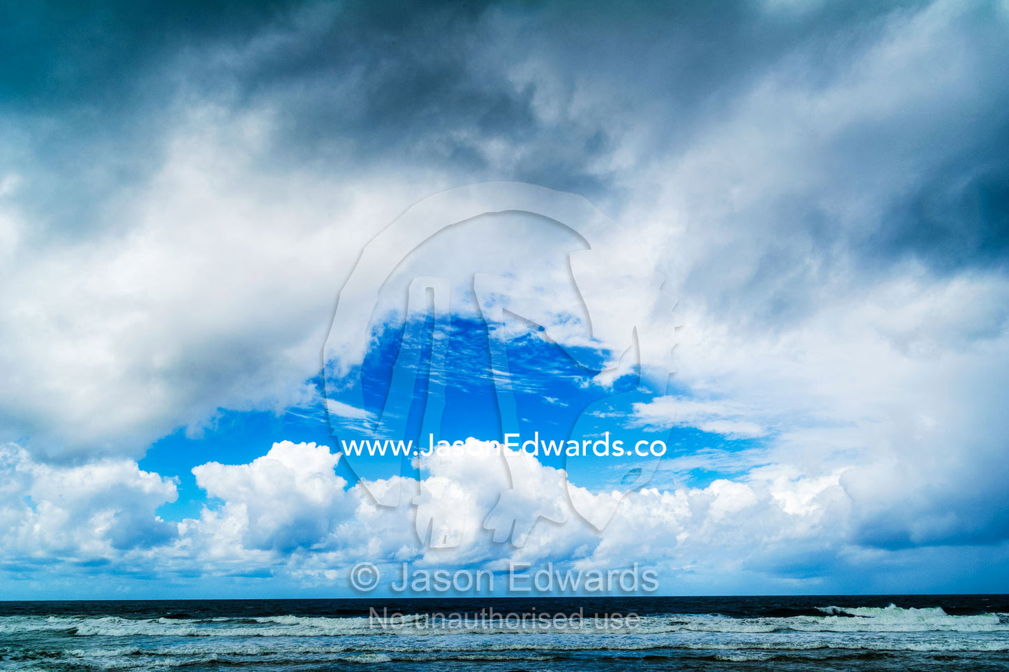 A patch of blue sky appears over an ocean during a storm. Yaroomba Beach, Queensland, Australia.