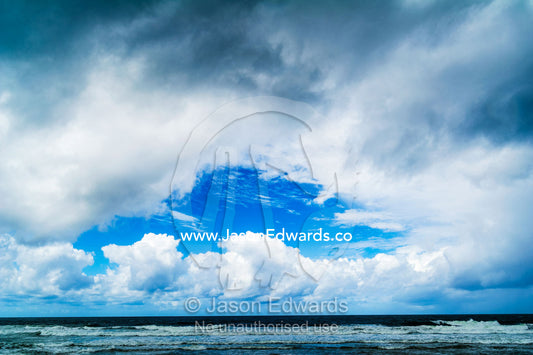 A patch of blue sky appears over an ocean during a storm. Yaroomba Beach, Queensland, Australia.