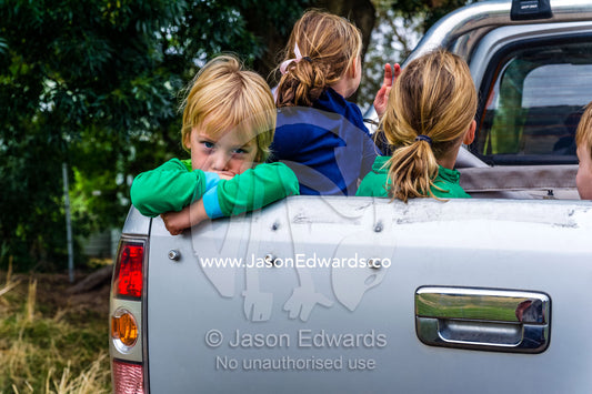 Children ride in the back of a utility vehicle on a farm. Euroa, Strathbogie, Victoria, Australia.