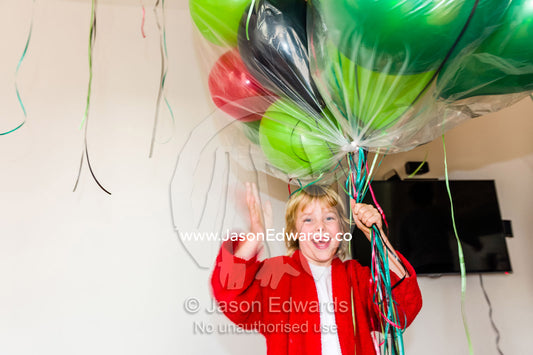 A boy decorating a house with party balloons for his birthday. Carlton North, Melbourne, Victoria, Australia.
