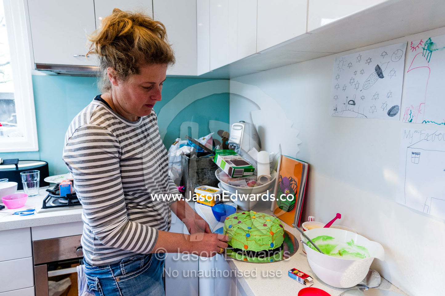 A mother decorating a birthday cake in the kitchen. Carlton North, Melbourne, Victoria, Australia.