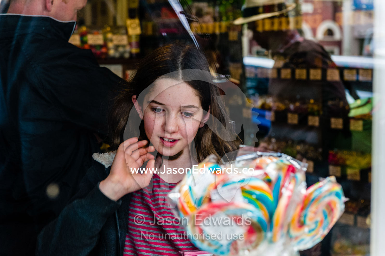 A girl choses a lollypop in a country town candy store. Maldon, Shire of Mount Alexander, Victoria, Australia.