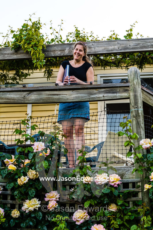 A woman looks down from a balcony over a rose garden. Castlemaine, Victoria, Australia.