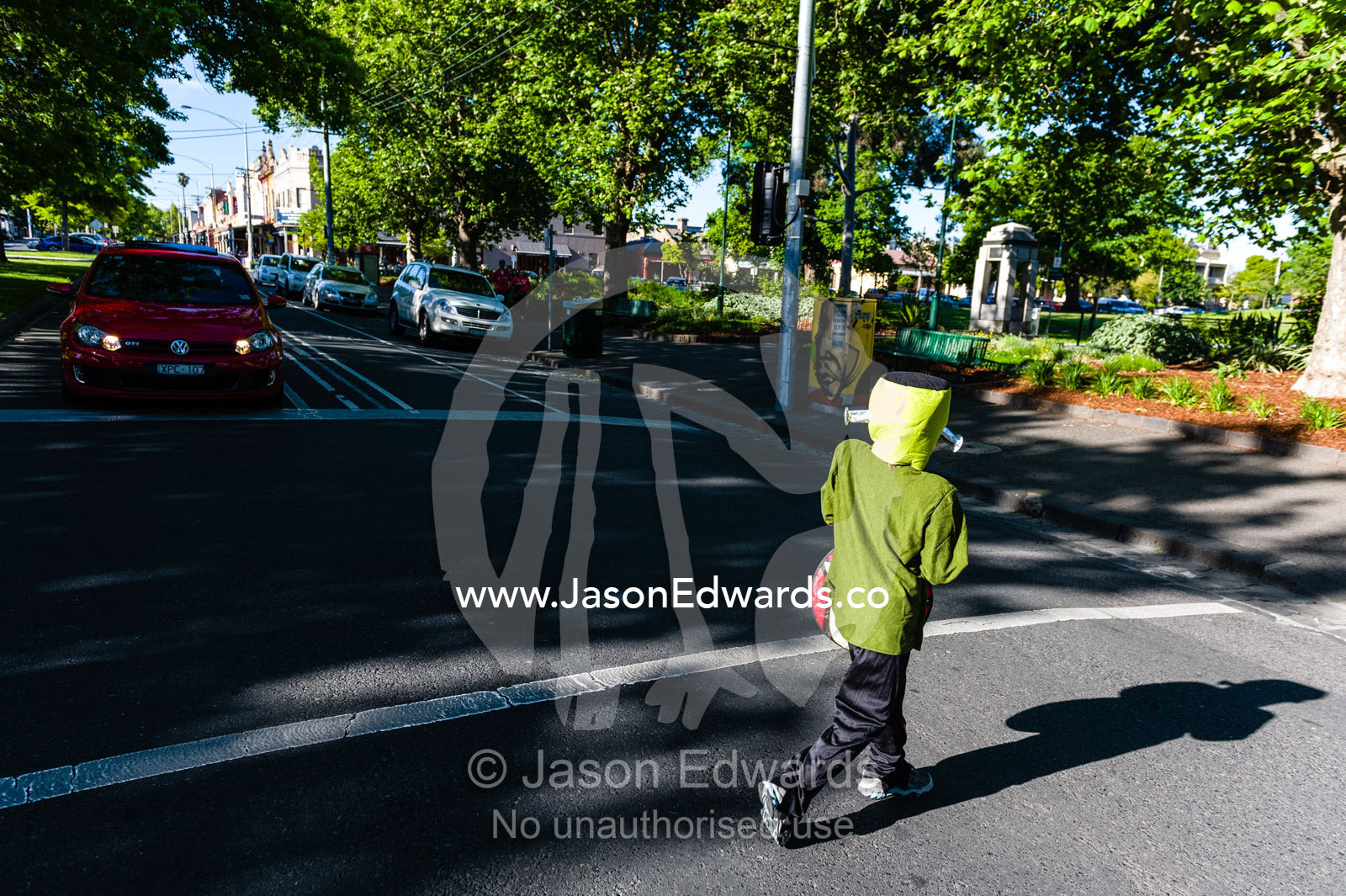 A boy dressed as Frankenstein crosses a road on his way to trick or treat on Halloween. Carlton North, Melbourne, Victoria, Australia.