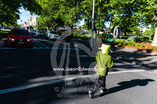 A boy dressed as Frankenstein crosses a road on his way to trick or treat on Halloween. Carlton North, Melbourne, Victoria, Australia.