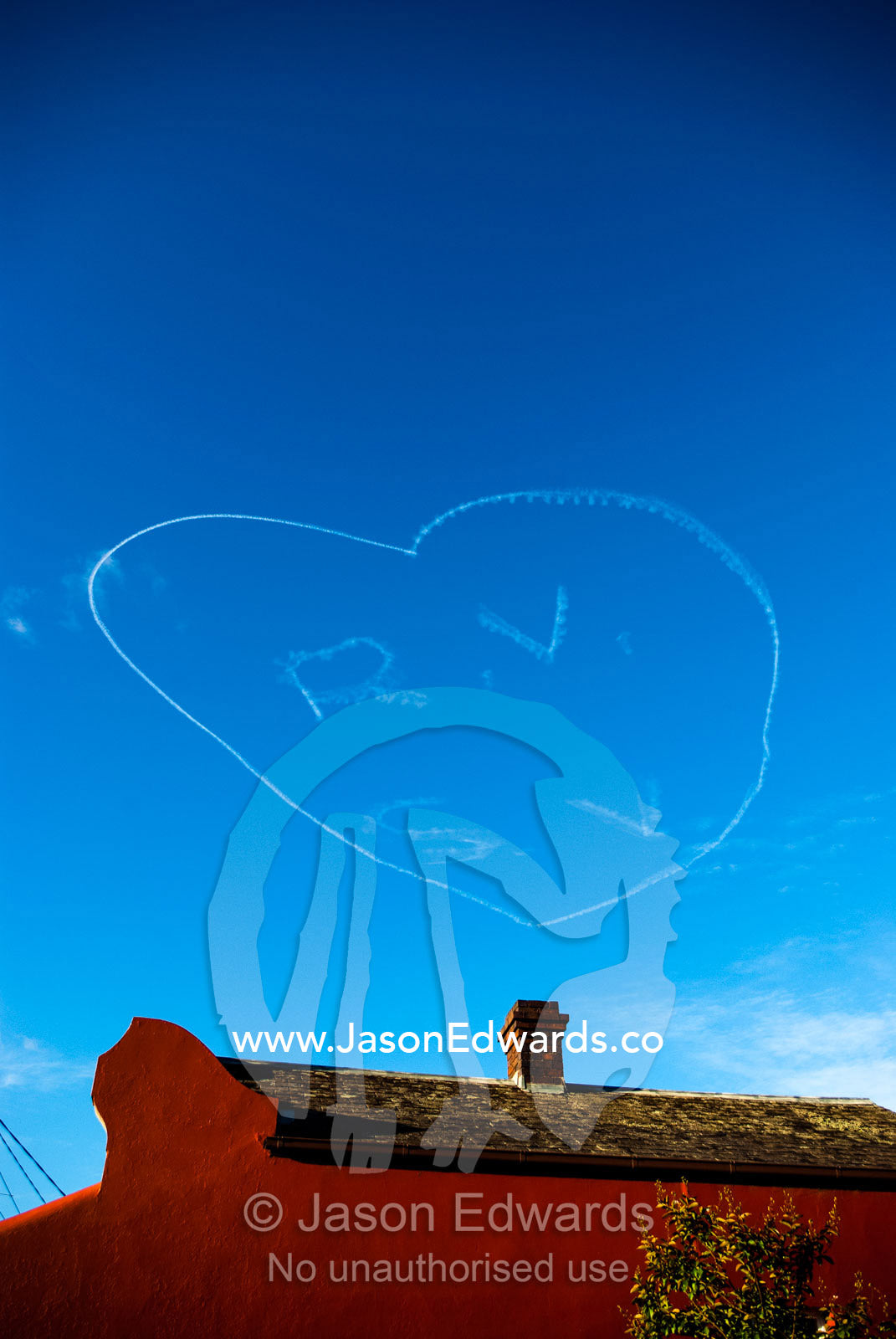 Sky writers draw a love heart and initials above a terrace house in a blue sky on valentines day. Carlton North, Melbourne, Victoria, Australia.
