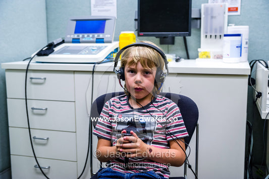 A boy listens for sounds in headphones during a hearing test in an audiologist clinic. The University of Melbourne Audiology Clinic, Carlton, Melbourne, Victoria, Australia.