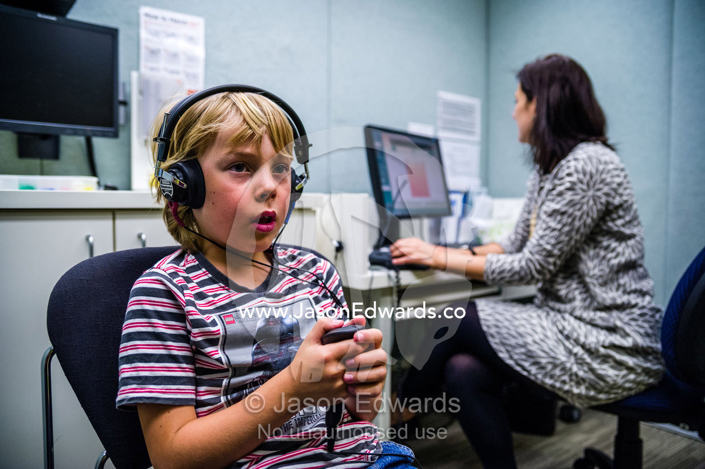 A boy concentrating whilst he listens for sounds in headphones during a hearing test in an audiologist clinic. The University of Melbourne Audiology Clinic, Carlton, Melbourne, Victoria, Australia.