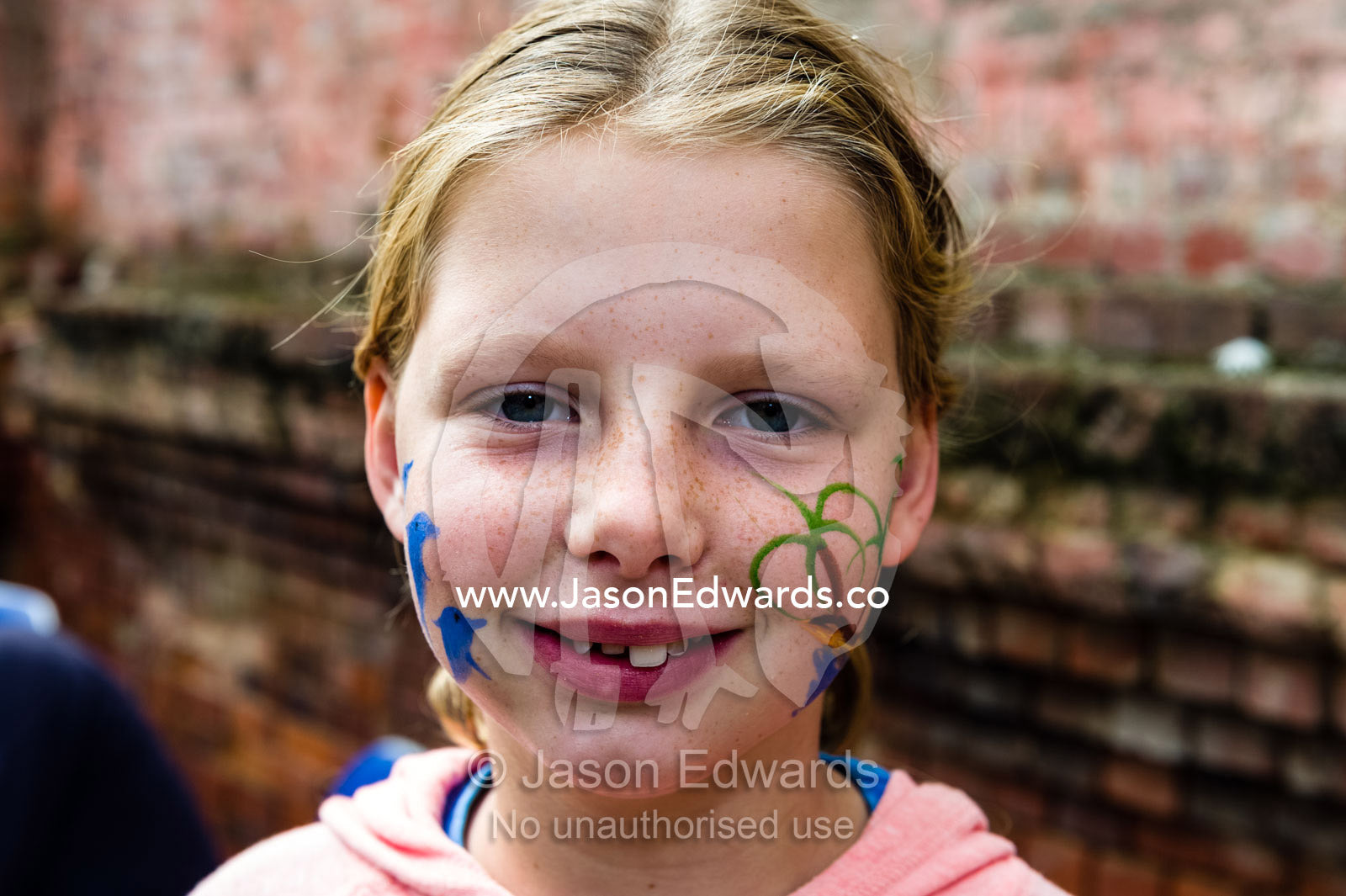 A smiling girl with dolphins painted on her face at an Easter carnival. Euroa Butter and Ice Factory, Euroa, Strathbogie, Victoria Australia.