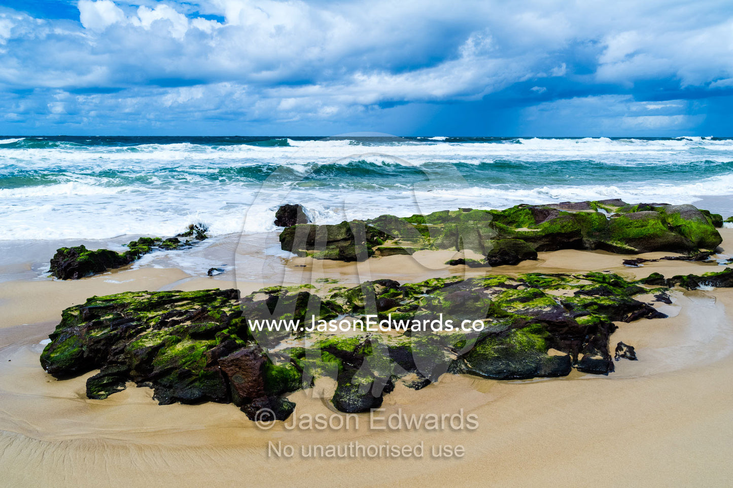 Seaweed covered rocks exposed on the beach at low tide. Point Arkwright, Yaroomba Beach, Queensland, Australia.