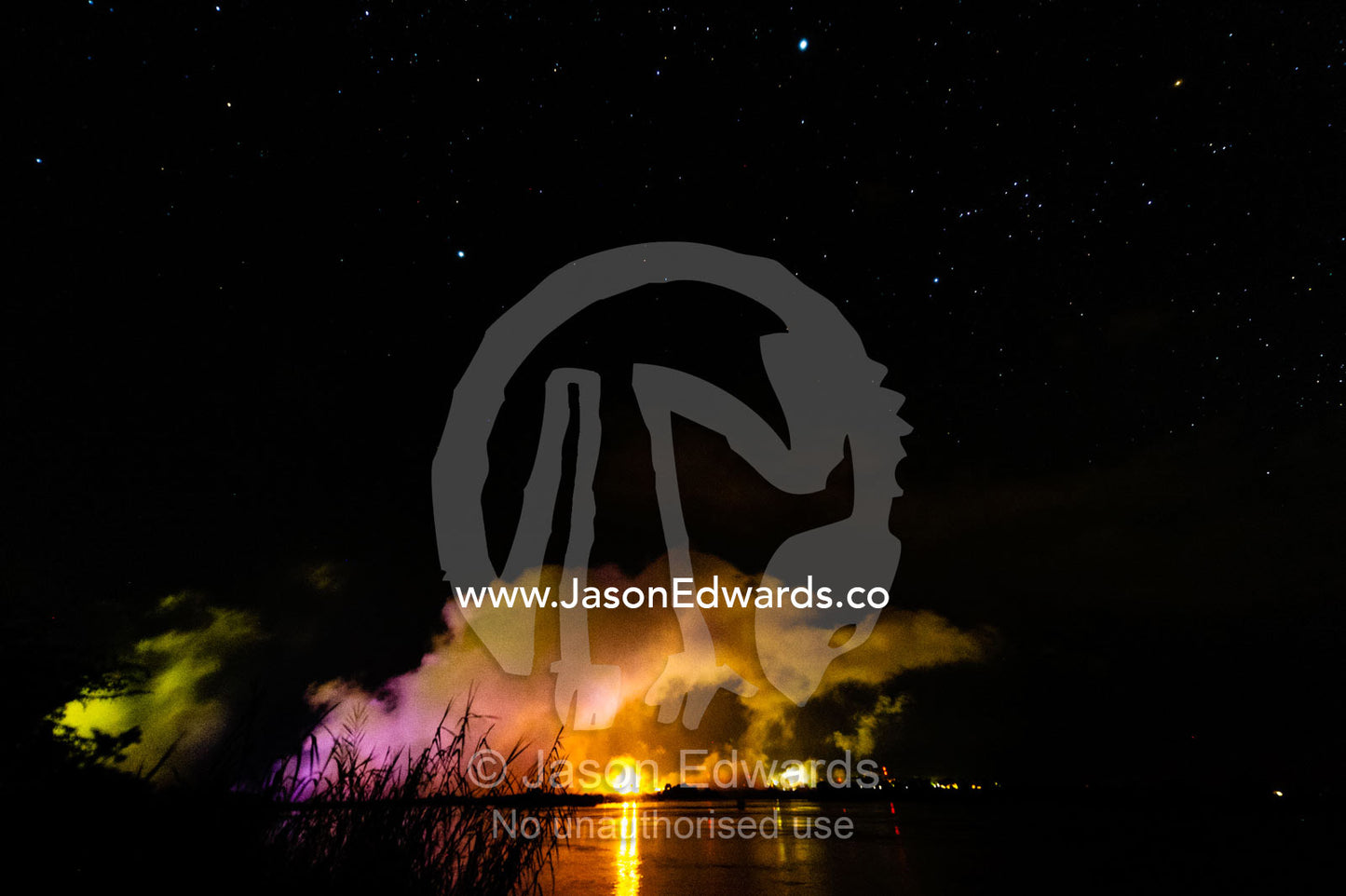 Floodlit mist rises from Victoria Falls over the Zambezi River at night. Zambezi River, Victoria Falls, Mosi-oa-Tunya National Park, Zambia.