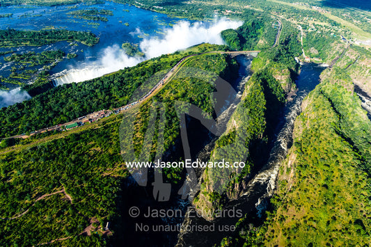 An aerial view of Victoria Falls and a winding gorge carved into a flat plain by the Zambezi River. Zambezi River, Victoria Falls, Mosi-oa-Tunya National Park, Victoria Falls National Park, Zambia.