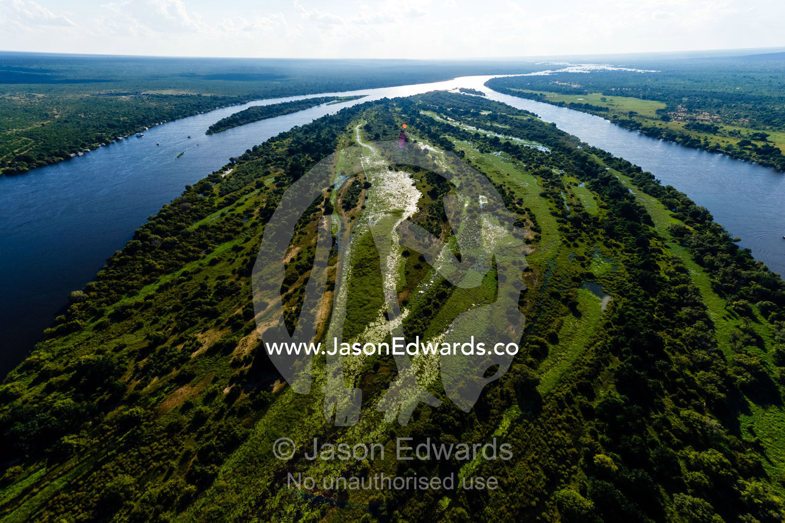 The wide Zambezi River flowing around a large island. Zambezi River, Mosi-oa-Tunya National Park, Victoria Falls National Park, Zambia.