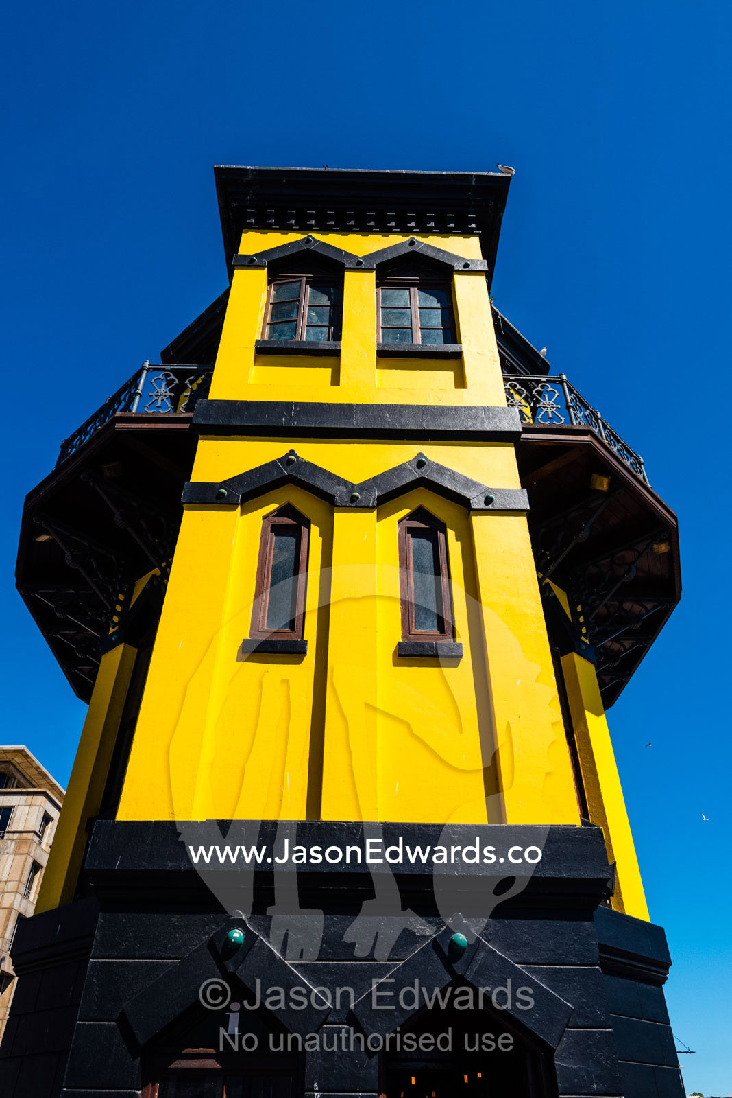 A bright yellow historic clock tower on a sunny wharf. Cape Town, Victoria and Alfred Waterfront, Western Cape, South Africa.