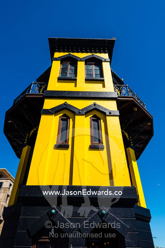 A bright yellow historic clock tower on a sunny wharf. Cape Town, Victoria and Alfred Waterfront, Western Cape, South Africa.