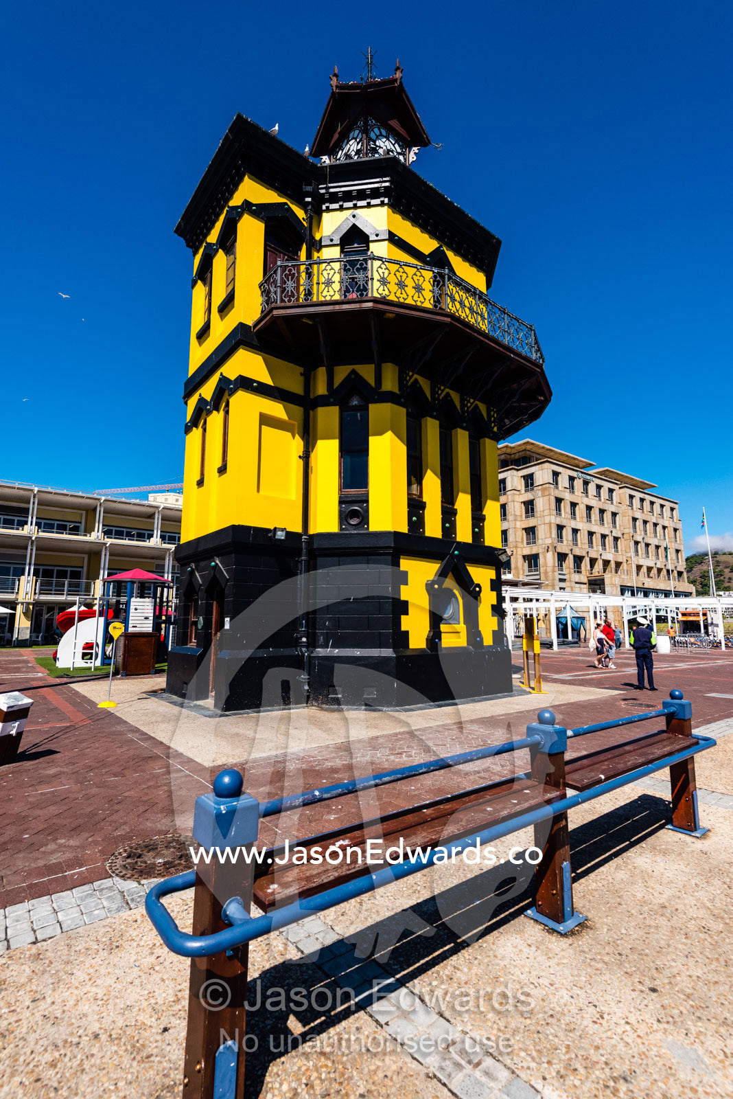 A bright yellow historic clock tower on a sunny wharf. Cape Town, Victoria and Alfred Waterfront, Western Cape, South Africa.