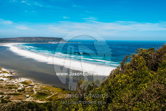 A wide sweeping ocean beach hidden among sand dunes. Noordhoek Beach, Cape Town, Chapmans Peak Drive, Western Cape, South Africa.