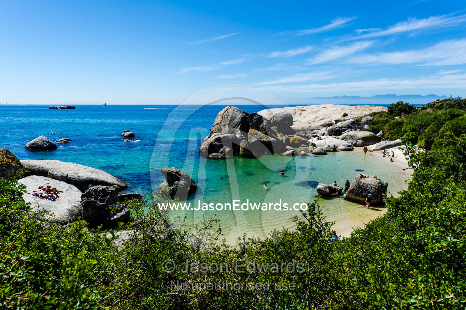 Tourists swimming between boulders in the clear waters of a sheltered bay. Boulders Beach, Cape Peninsula, Cape Town, Western Cape Province, South Africa.