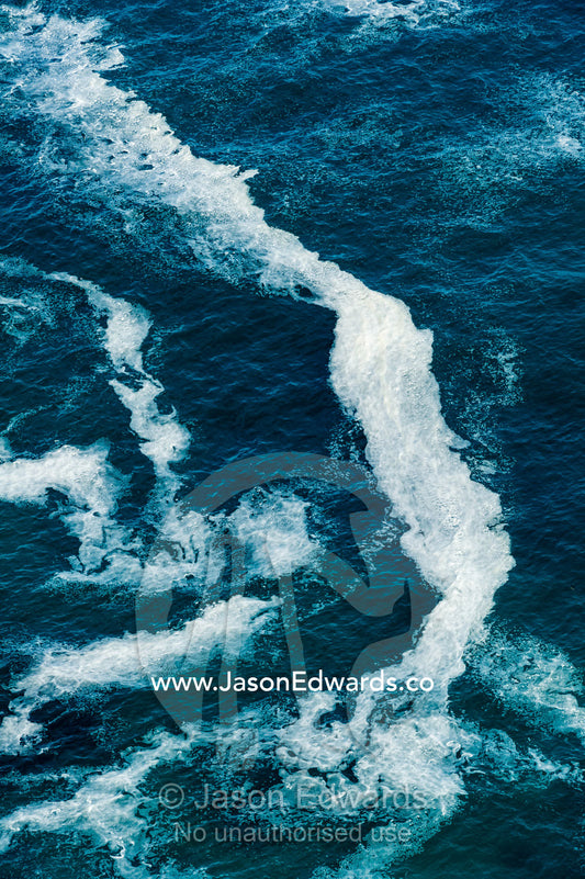 Wave foam trapped in currents along the base of coastal cliffs. Cape of Good Hope, Cape Point, Table Mountain National Park, Cape Peninsula, South Africa.