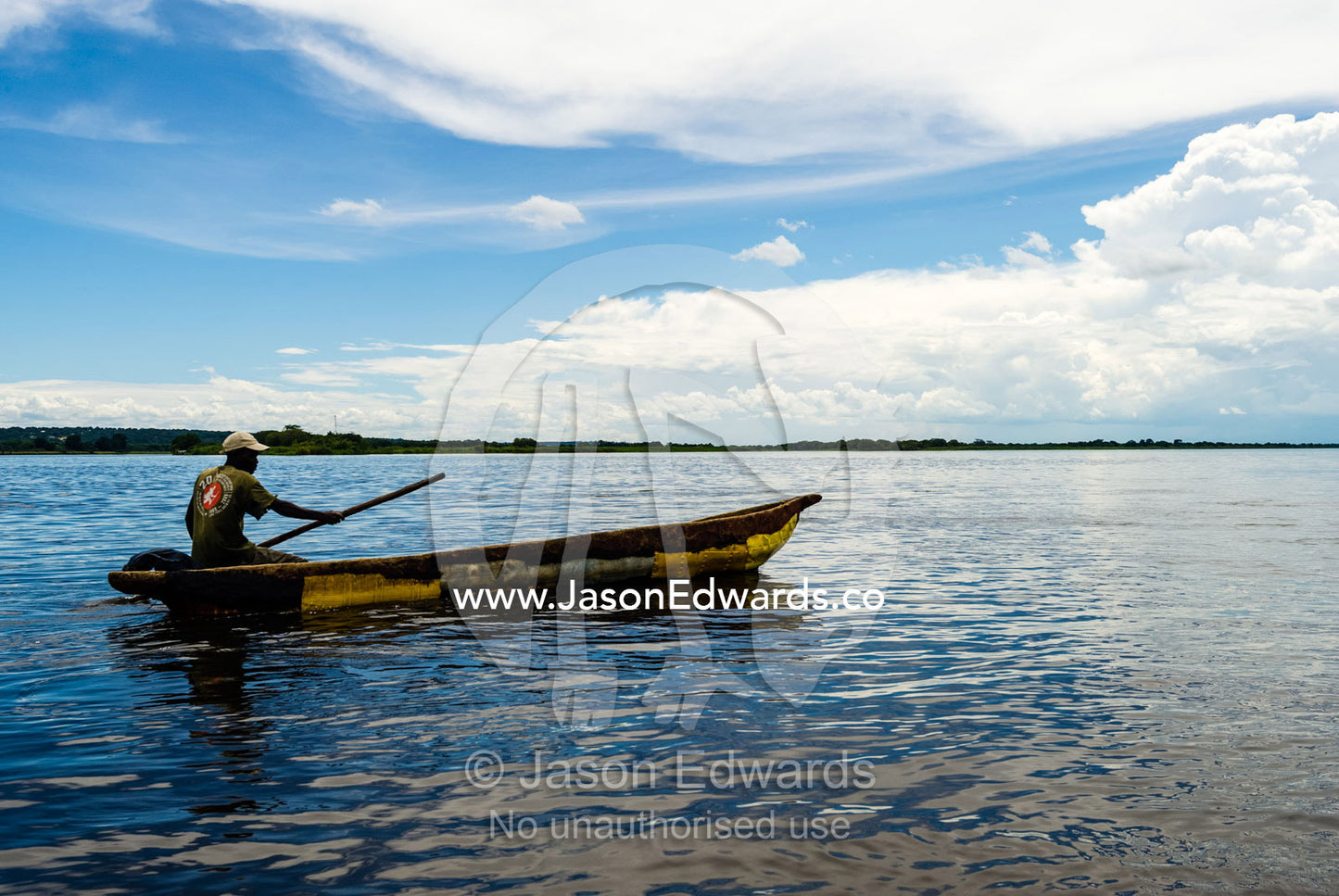 A fisherman paddling a canoe on a wide African river. Zambezi River, Kazungula, Southern Province, Zambia.