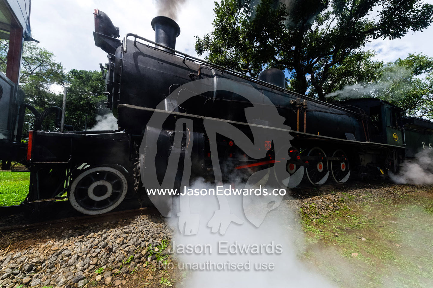 Steam pours from an antique train locomotive departing on a journey. Livingstone, Zambia.