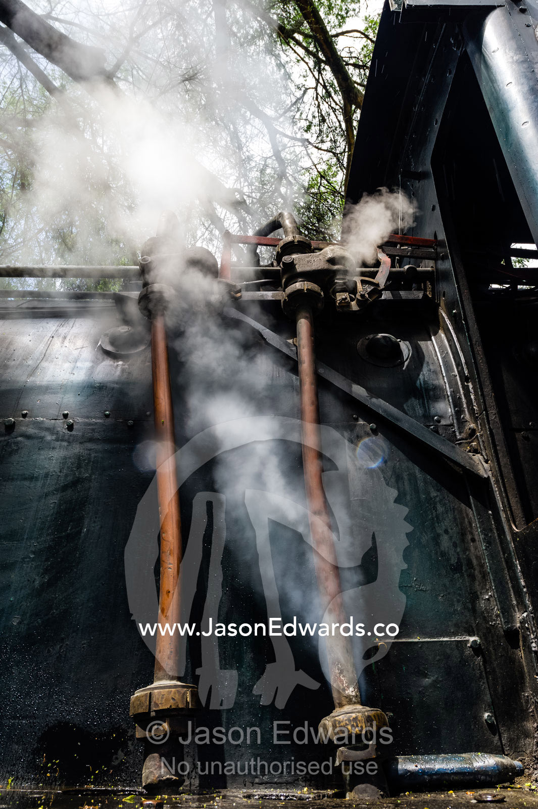 Steam pours from the boiler of an antique train locomotive waiting to begin a journey. Livingstone, Zambia.