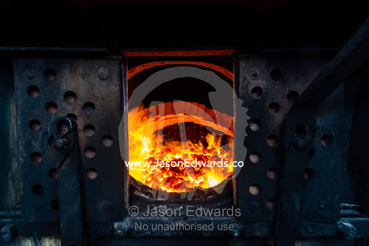 Glowing coals and fire inside the boiler of an antique steam train locomotive. Livingstone, Zambia.