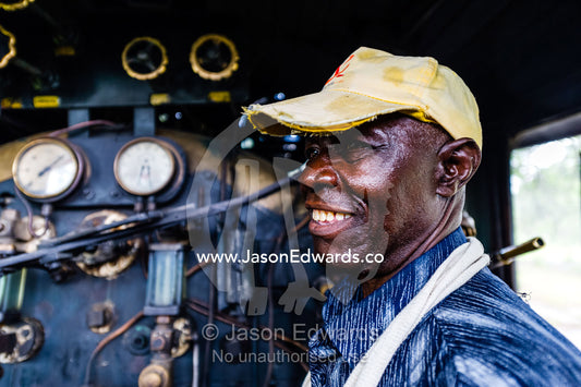 An antique steam train engine driver in the cab of the locomotive. Livingstone, Zambia.
