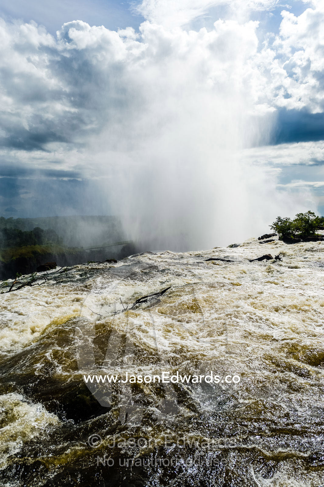 The rapids of the Zambezi River tumble over Victoria Falls sending up a plume of mist. Zambezi River, Victoria Falls, Mosi-oa-Tunya National Park, Zambia.