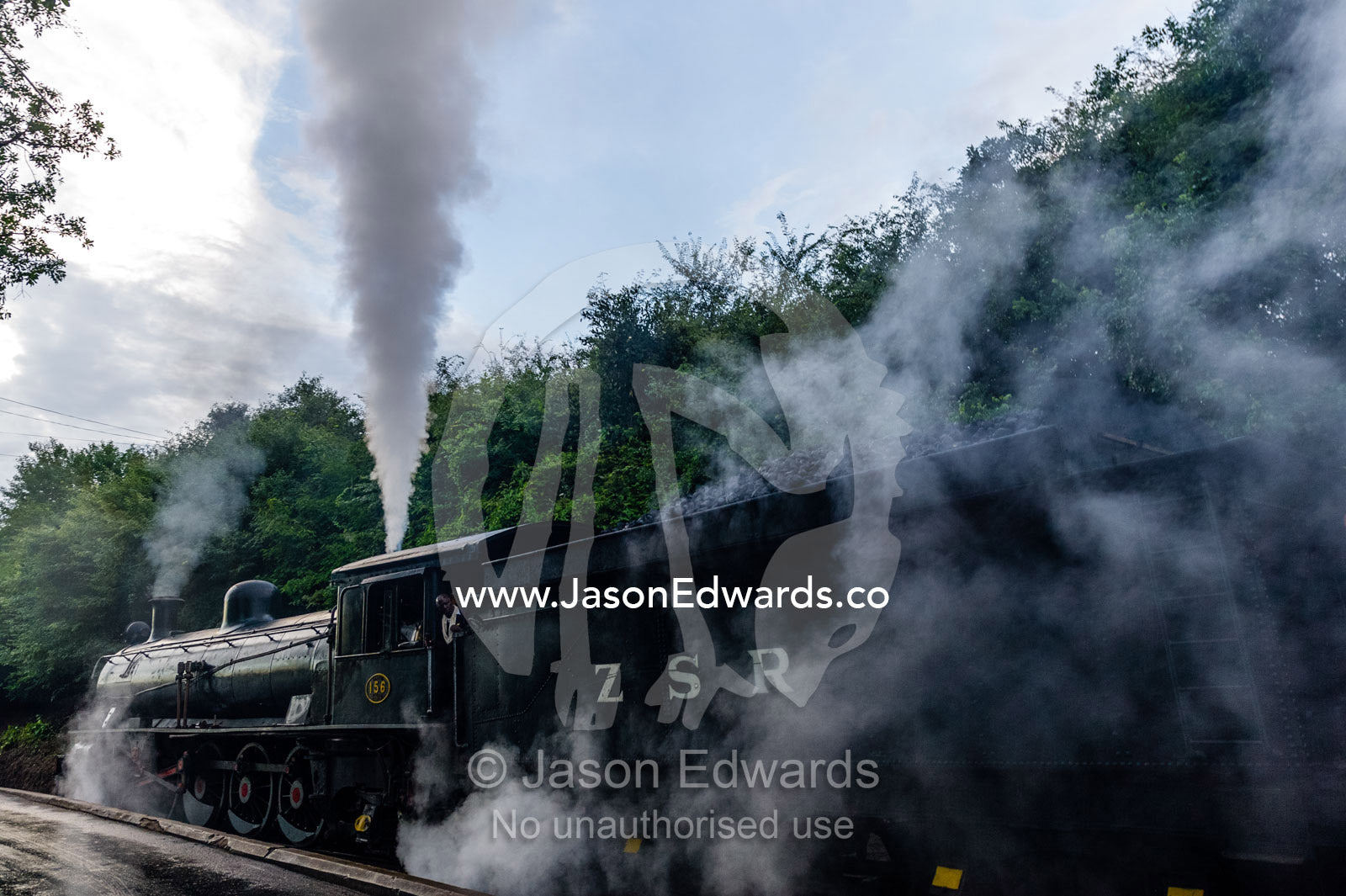 Steam pours from an antique train locomotive departing on a journey. Livingstone, Zambia.