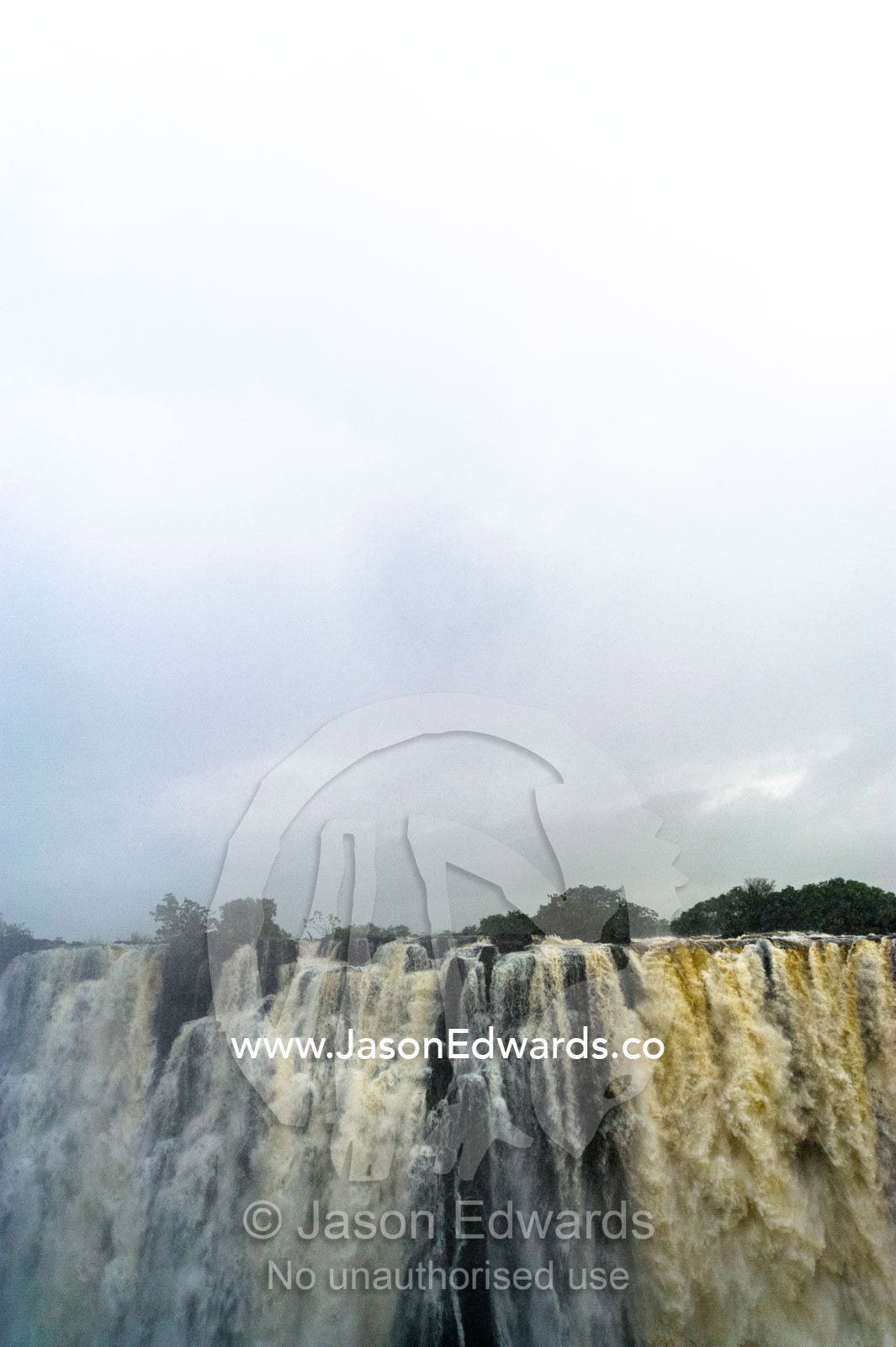 A rainstorm falls over the cascading Victoria Falls already in flood. Zambezi River, Victoria Falls, Mosi-oa-Tunya National Park, Zambia.