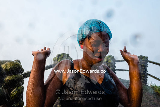 A happy lady dances in the drenching rain pouring down from Victoria Falls. Zambezi River, Victoria Falls, Mosi-oa-Tunya National Park, Zambia.