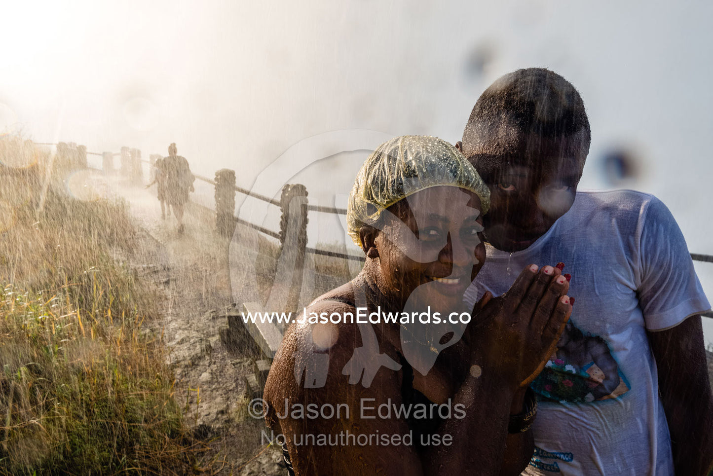 A happy couple standing in the drenching rain pouring down from Victoria Falls. Zambezi River, Victoria Falls, Mosi-oa-Tunya National Park, Zambia.