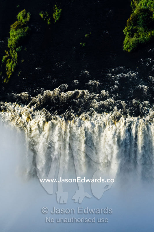 The flooded waters of the Zambezi River cascade in a curtain across the face of Victoria Falls. Zambezi River, Victoria Falls, Mosi-oa-Tunya National Park, Zambia.