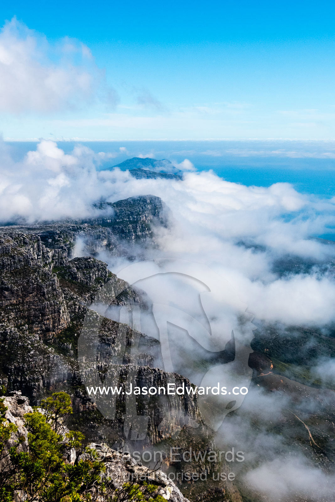 Clouds fill the valleys and gorges of a coastal mountain range overlooking the ocean. Table Mountain, Cape Town, Western Cape, South Africa.