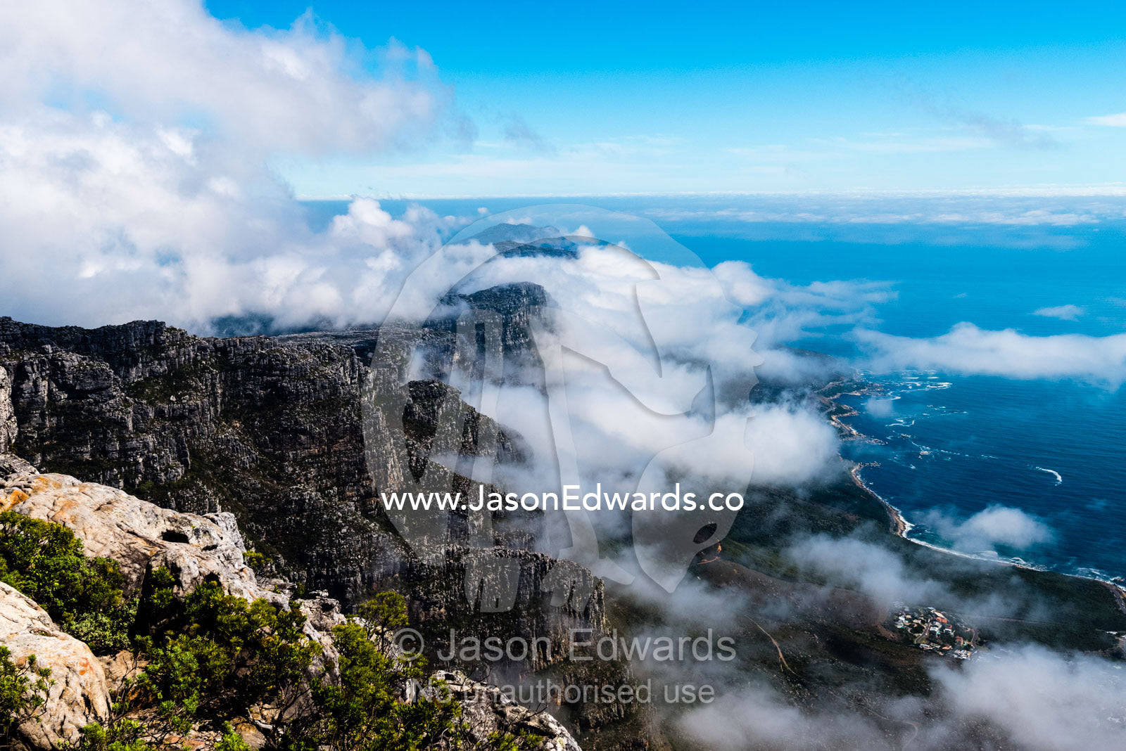 Clouds fill the valleys and gorges of a coastal mountain range overlooking the ocean. Table Mountain, Cape Town, Western Cape, South Africa.