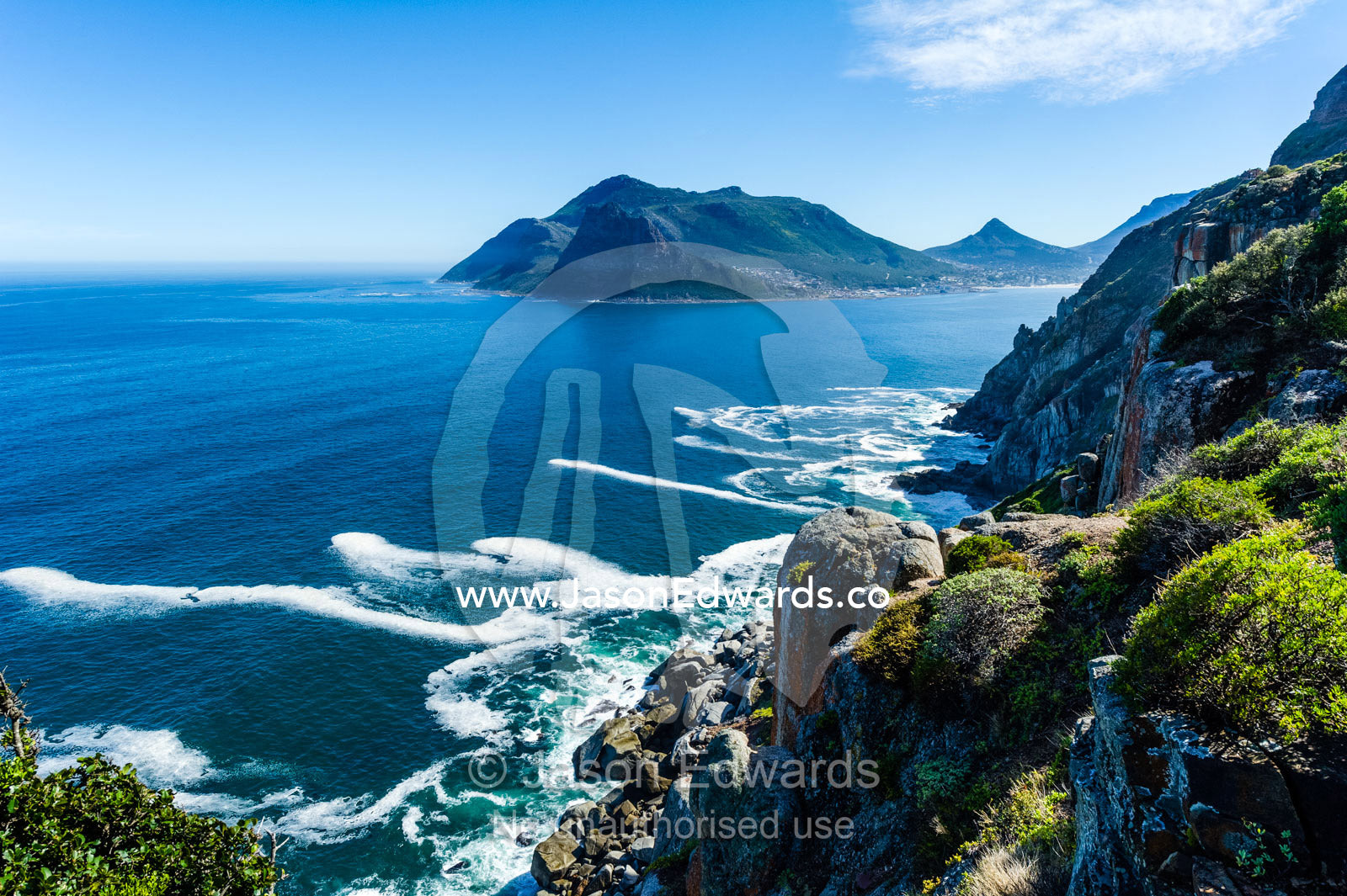 Wave foam trapped in currents along the base of coastal cliffs. Sentinel Peak, Hout Bay, Chapmans Peak Drive, Chapmans Peak Mountain Range, Cape Town, Western Cape, South Africa.